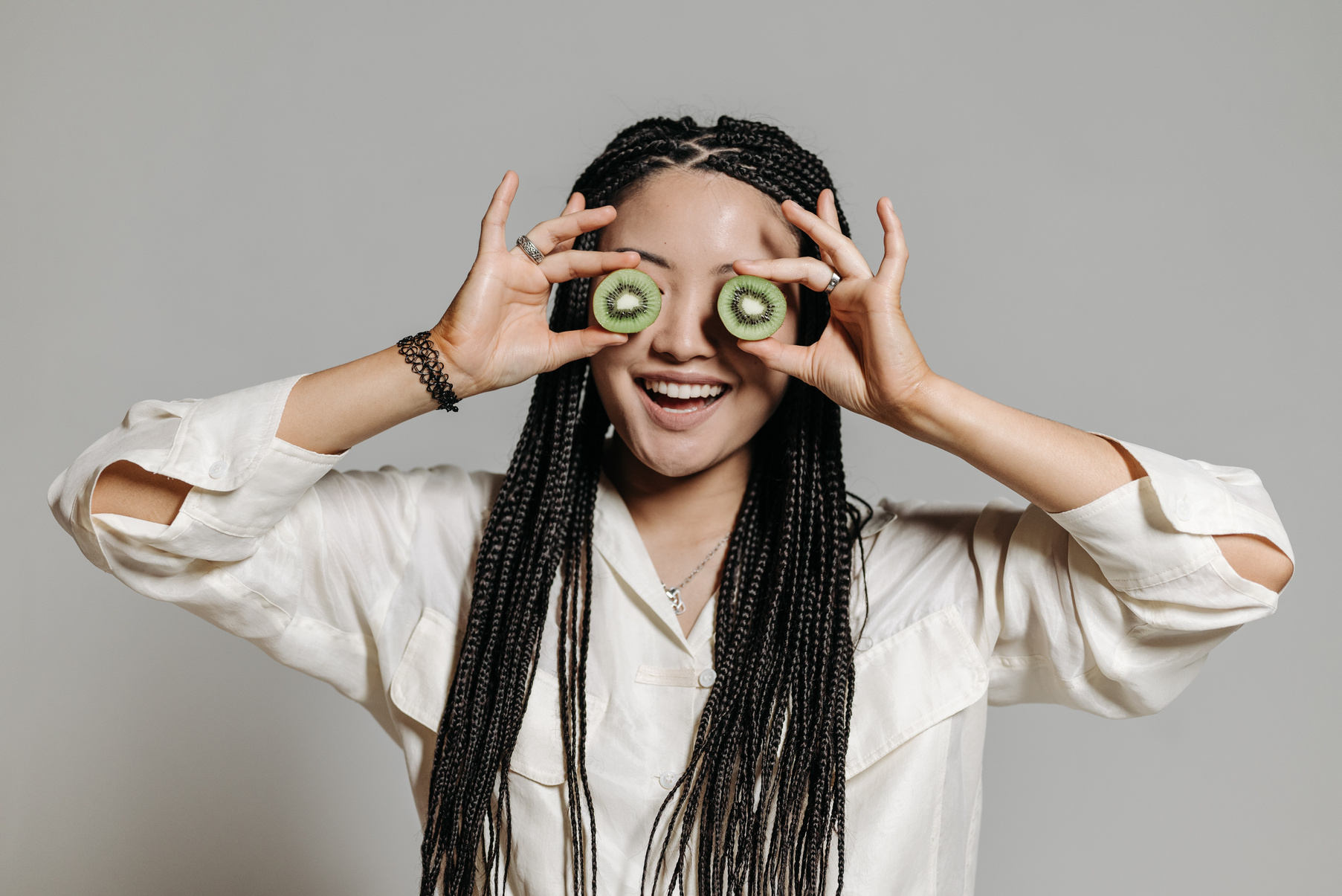 Young Woman Holding Slices of Kiwi Fruit Covering Her Eyes